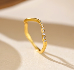 Détail macro d'une bague ondulée en argent S925 plaqué or avec de petits zircons cubiques
