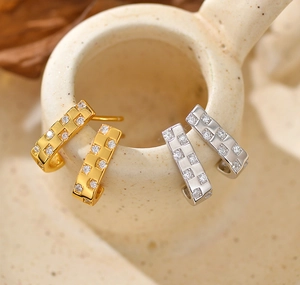 Macro-opname van 925 sterling zilveren J-oorbellen met zirkonia in schaakbordpatroon