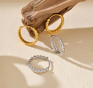 Close-up of S925 sterling silver hoop earrings in gold and silver finish on wood
