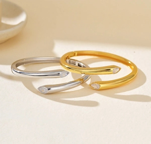 Macro detail of bypass open bangles featuring pear-cut cubic zirconia in gold and silver