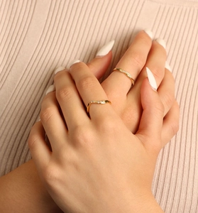 Gros plan de deux bagues ondulées dorées avec diamants portées par un mannequin