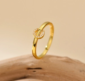 Macro shot of gold-plated horseshoe ring with pave-set cubic zirconia on a wooden base