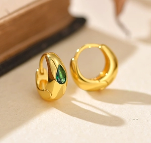 Vue détaillée de créoles dorées ornées d'une pierre de zircon vert émeraude en poire