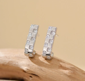 Macro-opname van de J-vormige 925 sterling zilveren oorbellen met sprankelend zircon-schaakbord