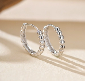 Macro shot of polished S925 sterling silver beaded hoop earrings with a clasp closure