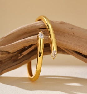 Macro detail of gold-plated pear-shaped zircon stones on a sleek wrap bangle