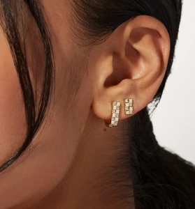 Detailopname van gouden geometrische oorbellen met vierkant zirkonia-pavé-patroon