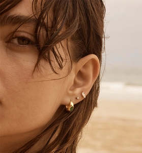 Gros plan sur la bague d'oreille dorée avec pierre émeraude et puce en feuille