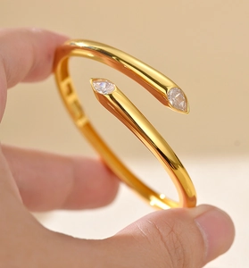 Macro detail of gold-plated bypass bangle with two sparkling pear-cut zircon stones