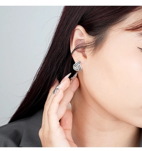 Close-up of geometric triangle stud earrings with shimmering stones and black enamel detail