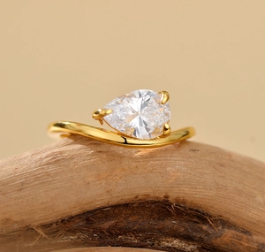 Macro detail of wave-shaped S925 silver ring with pear-cut zircon on natural wood