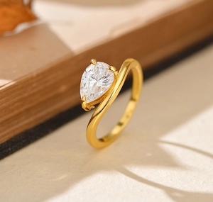 Macro detail of gold-plated wave ring featuring a teardrop-shaped pear-cut zircon stone