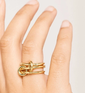 Dettaglio ravvicinato di un anello a tre strati dorato con micro-pavé di pietre in zircone