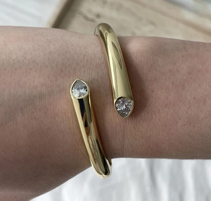 Detail of gold-plated cuff bracelet featuring dual pear-cut white zircon accents on the wrist