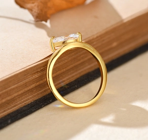 Detail of elegant gold S925 ring with emerald cut zircon set on book with autumn leaves