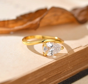Macro shot of gold wave-shaped S925 silver ring with a teardrop zircon on vintage book