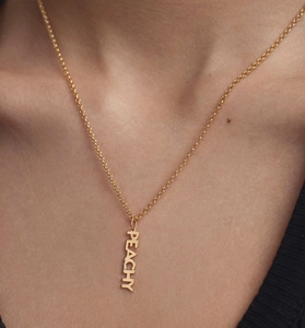 Close-up of a gold-plated S925 silver necklace featuring a vertical PEACHY letter pendant