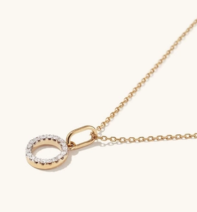 Macro detail of a gold S925 sterling silver circular pendant with micro-set pave crystals