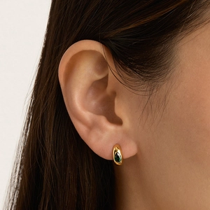 Boucles d'oreilles créoles dorées avec zircons gouttes émeraude sur mannequin