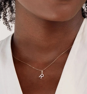 Close-up of S925 sterling silver letter R pendant with pavé diamonds on a gold chain