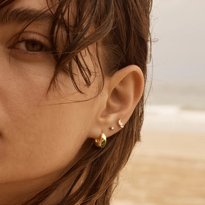 Boucles d'oreilles dorées avec pierre émeraude en forme de goutte sur mannequin