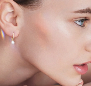 Detail of S925 silver pearl drop earring with cubic zirconia on a model for scale