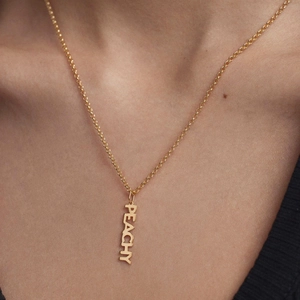 Minimalist gold chain necklace with vertical PEACHY letter pendant on female model