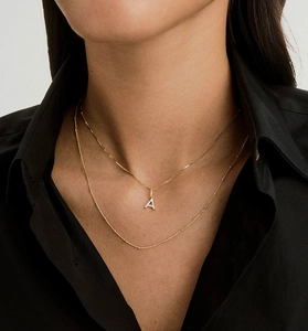 Close-up of layered 18K gold S925 silver necklace with sparkling pavé crystal letter A pendant