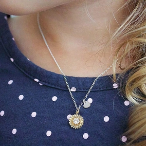 Gros plan du pendentif tournesol et cœur en argent S925 sur une chaîne en métal fin