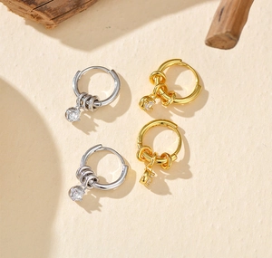 Macro shot of gold and silver plated hoop earrings with movable rings and round zircon drops