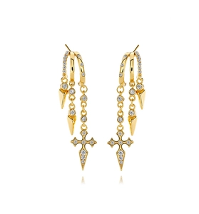 Detailed macro of gold layered earrings with sparkling zircons and a cross pendant