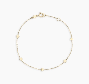 Detail of delicate gold heart charm bracelet with adjustable spring ring clasp and 5 hearts