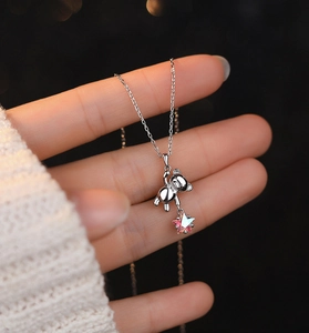 Close-up of S925 sterling silver bear pendant with iridescent pink star gem on hand