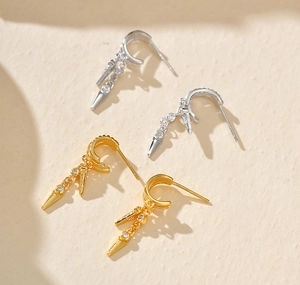 Macro detail of double-layer studded earrings with crystals in gold and silver finish