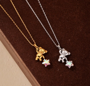 Detailed view of silver and gold 3D bear pendants with iridescent stars and zircon stones