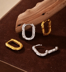 Detail view of oval sterling silver earrings with irregular lava texture in gold and silver