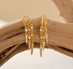 Macro detail of gold tassel drop earrings with sparkling rhinestones on wood
