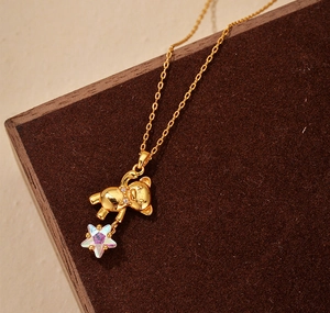 Detailed close-up of a golden teddy bear pendant with a sparkling iridescent star gem
