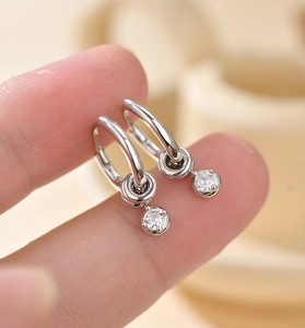 Macro detail of S925 sterling silver hoop earrings with a sparkling zircon pendant