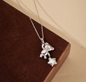 Close-up of S925 silver necklace featuring a 3D bear holding a shimmering opal star pendant
