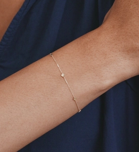 Close-up of a minimalist S925 sterling silver chain bracelet with three tiny heart charms
