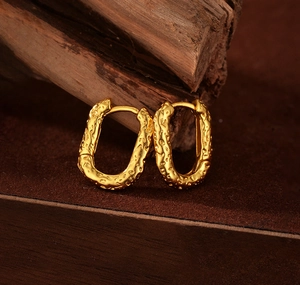 Macro view of gold lava-textured oval hoop earrings with vintage irregular finish