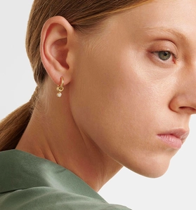 Detail of a minimalist gold hoop earring with a round clear gemstone on a female model