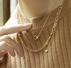 Detailansicht der dreilagigen Goldhalsketten mit Ringen und einem Kristallanhänger
