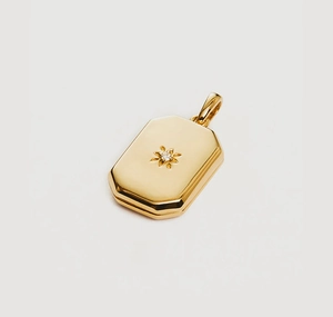 Detailed macro view of a gold-plated square locket pendant with an engraved starburst center