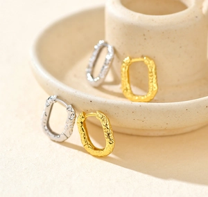 Macro detail of textured oval S925 sterling silver earrings in gold and silver finish