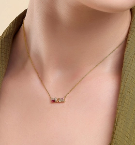 Close-up of golden S925 silver necklace with red and pink zircon gems on a model