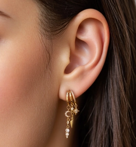 Close-up of three-piece gold stud set featuring moon star and cone charms on ear