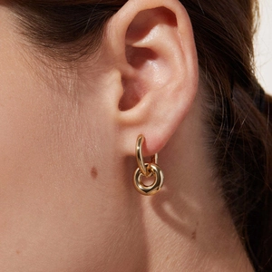 Close-up of elegant gold-plated double hoop earrings worn by a model in warm lighting