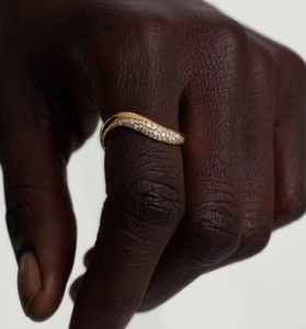 Macro shot of wavy gold zircon ring showing detailed stone setting on dark skin tone